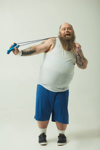 无忧无虑的胖男人玩跳绳照片