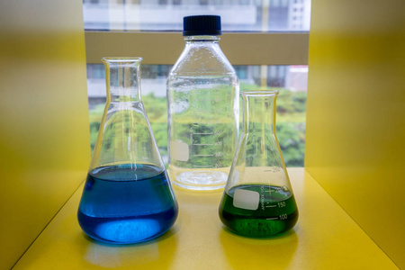 黄架玻璃烧杯中的蓝绿溶液照片