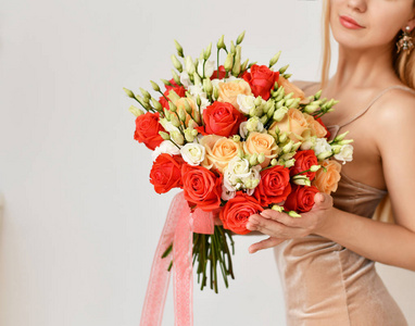 美丽的妇女举行红色和粉红色的玫瑰花束幸福微笑的灰色