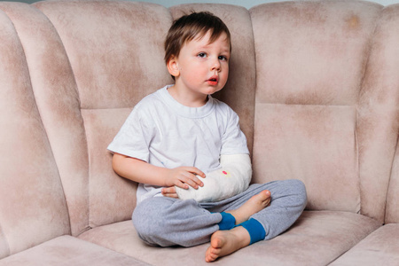 一个小男孩坐在椅子上, 胳膊断了, 在石膏上。医院。医学。危险。痛苦。折断四肢。