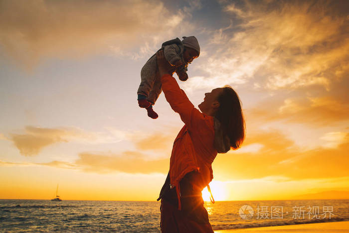 海上海滩日落时的母亲和婴儿剪影