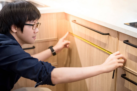 使用卷尺测量家具的亚洲青年男子