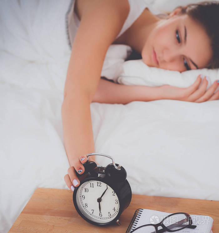 美丽的年轻女子躺在床上舒舒服服地和幸福