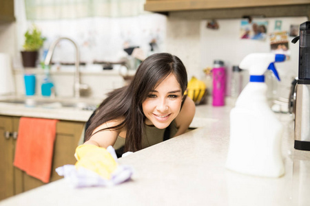 特写微笑的年轻主妇清洁肮脏的厨房柜台与抹布