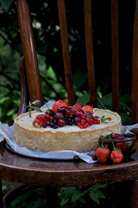 在一个绿色的花园中的自然水果馅饼与草莓和其他浆果。在老式的木椅上