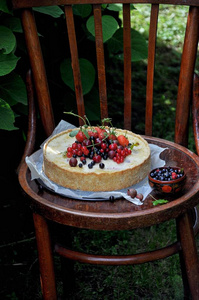在一个绿色的花园中的自然水果馅饼与草莓和其他浆果。在老式的木椅上