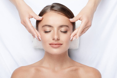 按摩肌肤拥有完美肌肤的年轻女子面部按摩, 手上的脸, 皮肤护理, 水疗