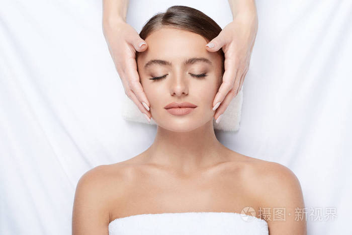 拥有完美肌肤的年轻女子面部按摩, 手上的脸, 皮肤护理, 水疗程序和