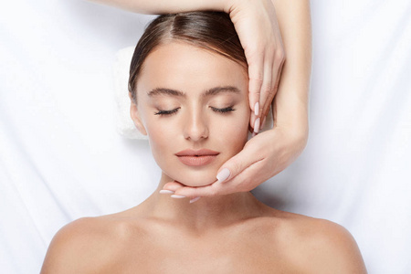 拥有完美肌肤的年轻女子面部按摩, 手上的脸, 皮肤护理, 水疗程序和