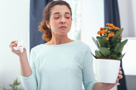 年轻女子看着开花植物怀疑