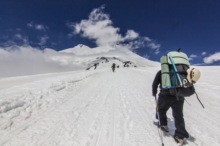 男子背着背包爬上雪高加索山脉的 elbrus