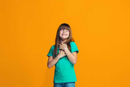 快乐的少女站着, 微笑着面对橙色背景
