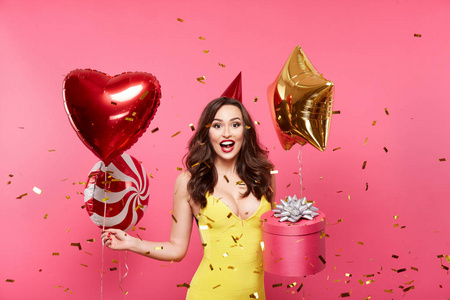 快乐的年轻女子气球和礼品盒摆在粉红色背景