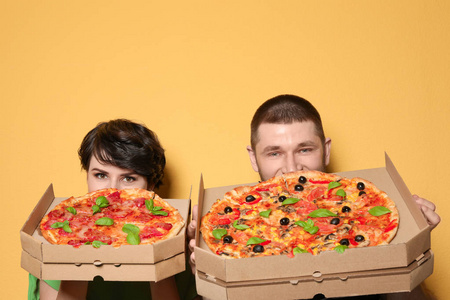 有吸引力的年轻夫妇与美味的比萨饼的颜色背景