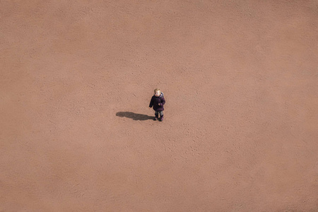 小孩子站在沙质沙漠的中间, 一个概念背景