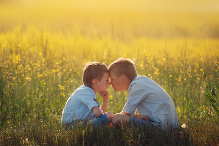 两个小男孩朋友在日落的夏天看着对方。兄弟爱。概念友谊