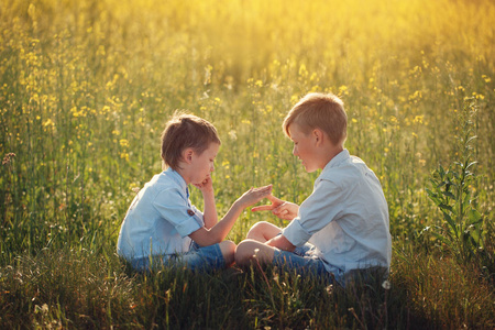 两个小男孩朋友玩石头, 剪刀, 纸游戏在夏天的日子。娱乐和休闲活动的概念