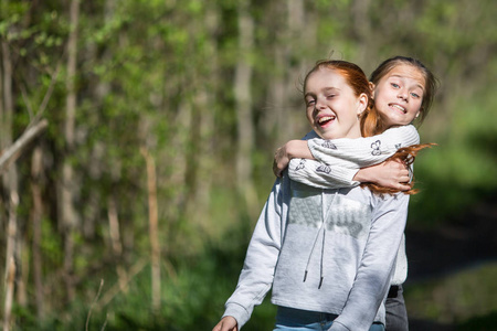 两姐妹十几岁的女孩朋友拥抱和乐趣在公园夏天