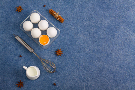 烘焙烹饪组合鸡蛋蛋黄一杯牛奶香料肉桂茴香咖啡豆厨房工具扫蓝色背景。水平方向, 复制空间的位置