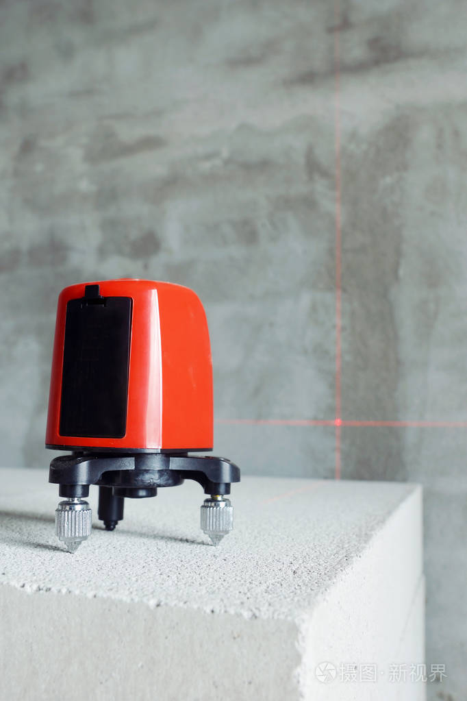 激光水平仪站在气孔混凝土装置砖上施工.专注于工具