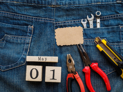 木块日历5月1日和细木工工具的牛仔纹理背景。劳动节概念