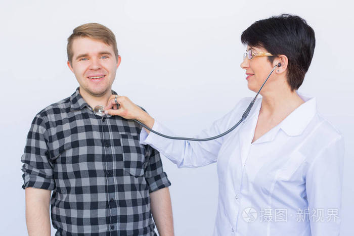 医生听欢快的年轻病人胸部与听诊器在白色背景