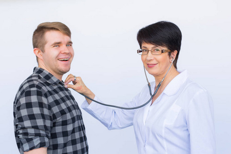 医疗, 体检, 人和医学概念-年轻人和医生与听诊器听心跳超过白色背景