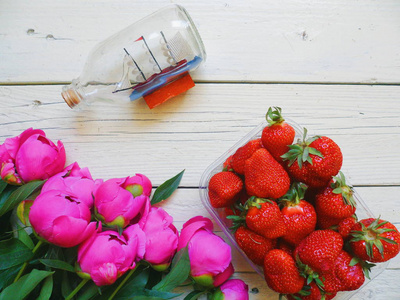 粉红色牡丹花, 草莓浆果和纪念品形式的游艇在一个白色的背景瓶子