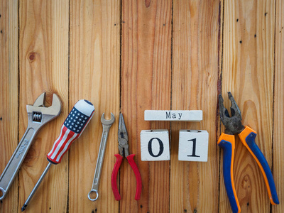 木块日历5月1日和细木工工具在木桌纹理背景。劳动节概念
