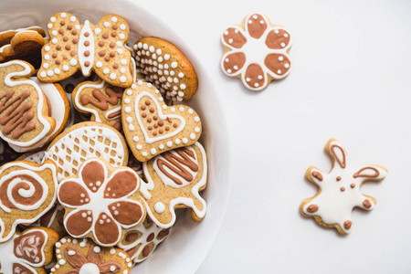姜饼饼干的形状复活节兔子, 心, 蝴蝶和花朵, 覆盖着白色和巧克力糖衣糖, 白色的表面上的白色盘子