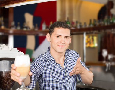 英俊的年轻的微笑酒保服务一杯美味的 cockta