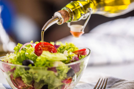 橄榄油倒进碗里的新鲜的蔬菜沙拉