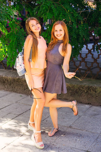 两个可爱的女孩在他们的手漂亮的礼服和太阳镜的真诚微笑