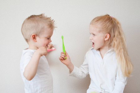 婴儿清洁牙齿。小可爱的金发女孩和男孩与刷牙。有趣的 lifestile 玩牙医游戏。孩子们笑了。卫生保健牙科卫生