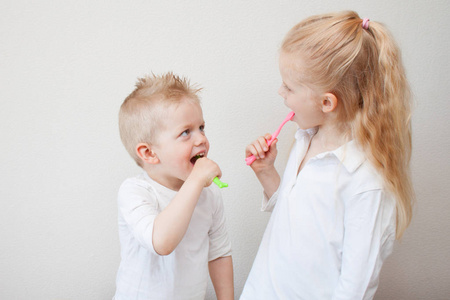 小金发男孩和女孩刷牙。兄弟姐妹。卫生保健牙科卫生