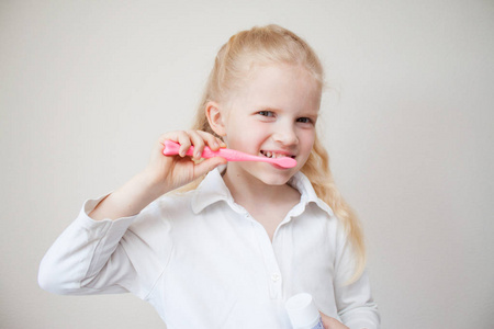 可爱的金发小男孩 girlbrushing 牙齿。手里拿着牙膏