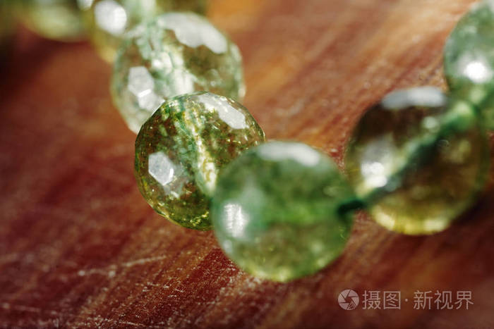 天然绿玉软玉石珠在木质表面。绿草彩圆石珠微距形象