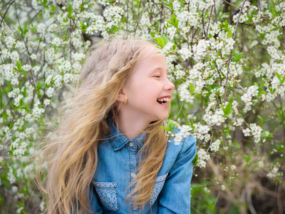 一个女孩在樱桃的肖像。女孩与她的头发在一个樱桃花花园的牛仔衬衫。笑的女孩的肖像