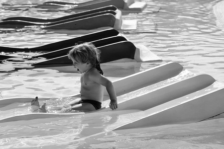 在水上公园娱乐。快乐可爱的小男孩从蓝色滑水幻灯片
