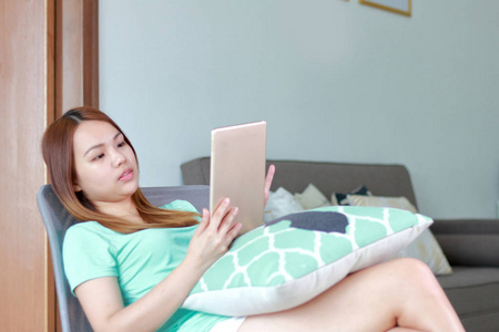 年轻妇女在家使用片剂。平板电脑是一种比笔记本小但比智能手机更大的无线触摸屏个人电脑。