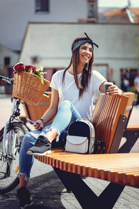 骑自行车的年轻妇女用智能手机和喝咖啡的花篮