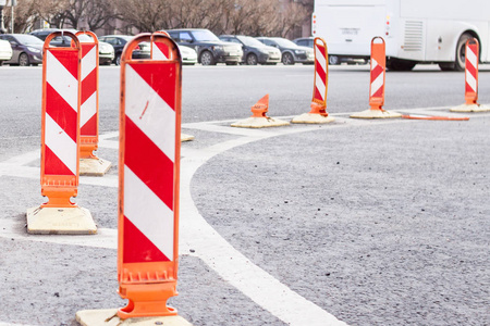 道路工作。橙色交通锥在街道的中间。交通安全建设大修标志。汽车和白色公共汽车