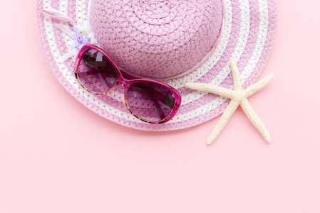 沙滩配件, 包括海星, 粉红色太阳镜和紫色沙滩帽在青色纸背景下的暑假和假期概念
