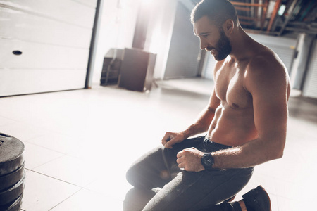 在车库健身房重硬训练后休息的年轻疲惫肌肉人