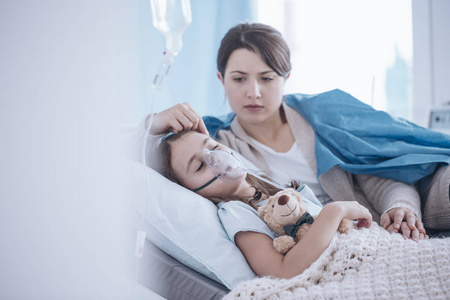 担心母亲支持睡眠生病的孩子与氧气面罩和毛绒玩具