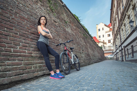 女孩在墙上的背景自行车。体育和健身概念