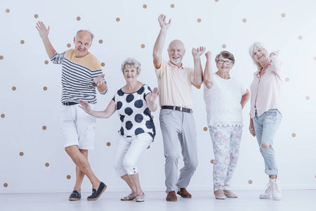 快乐的老年人跳舞反对白色背景与黄金点