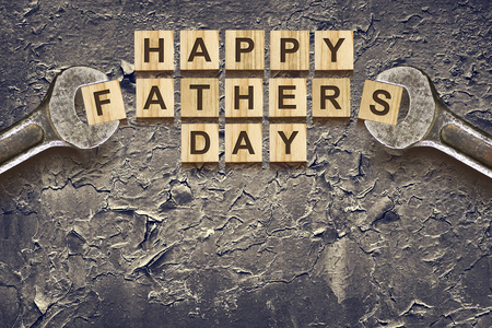 快乐的父亲节题字在木立方体与工作工具在老绘的铁。问候和礼物。假期