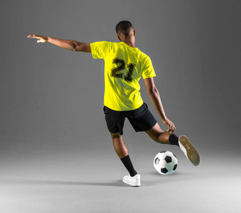 足球运动员黑皮肤的男子踢踢球在黑暗的背景下