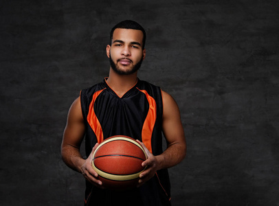 一个年轻的非洲裔美国篮球运动员在黑暗背景下隔离运动的肖像